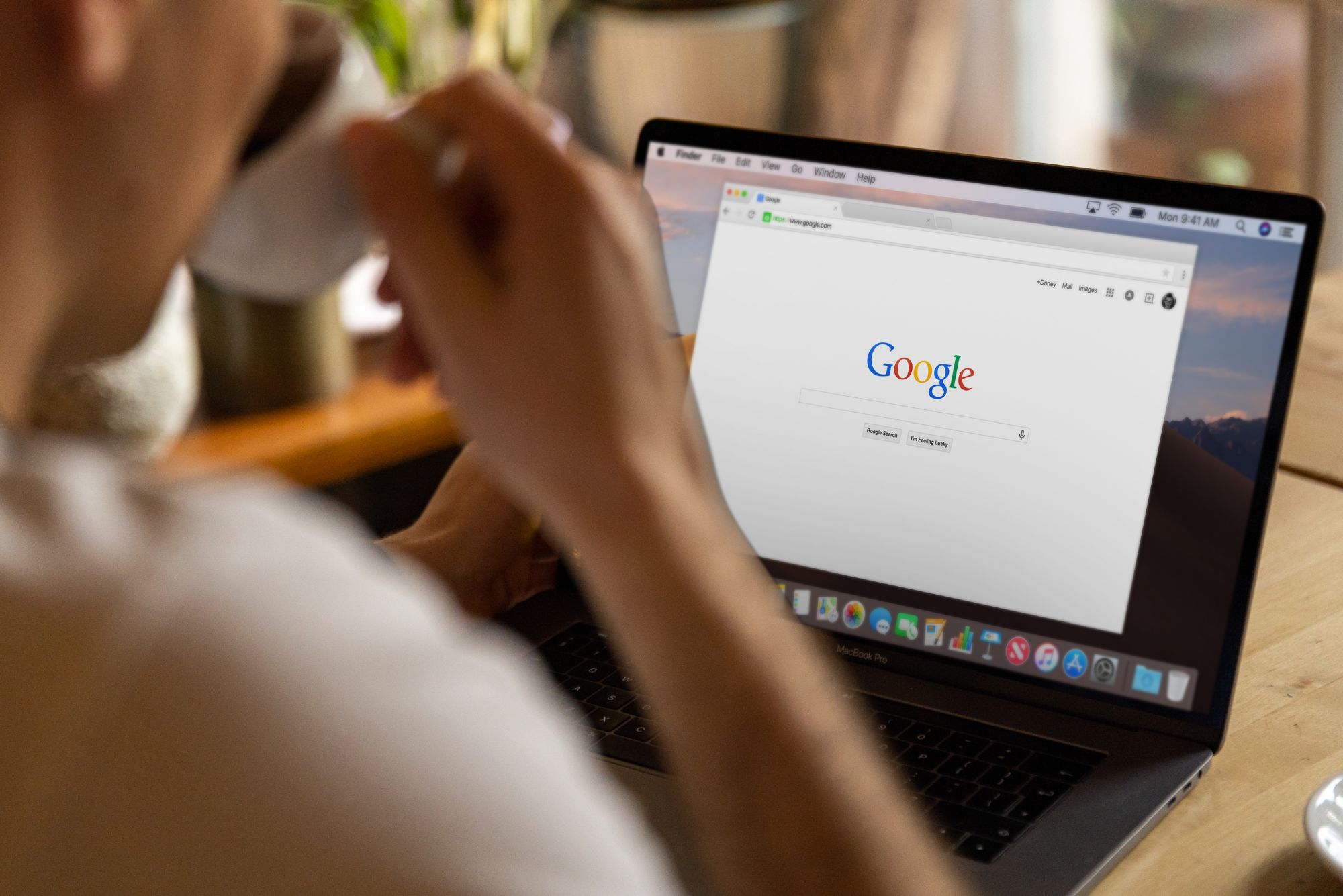 A business owner drinks coffee while sitting at a laptop, going through their Google ads checklist.