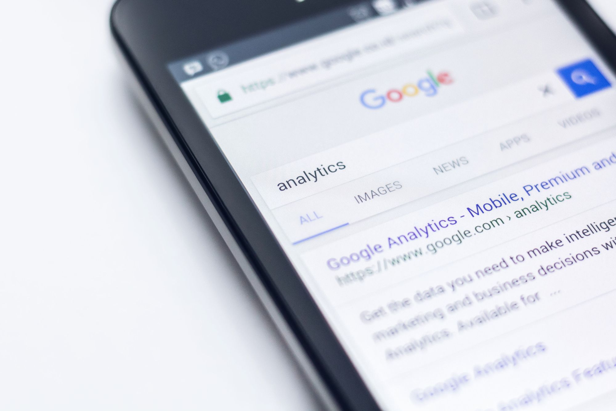 A phone sits on a table displaying a search history for the Google analytics 4 upgrade.