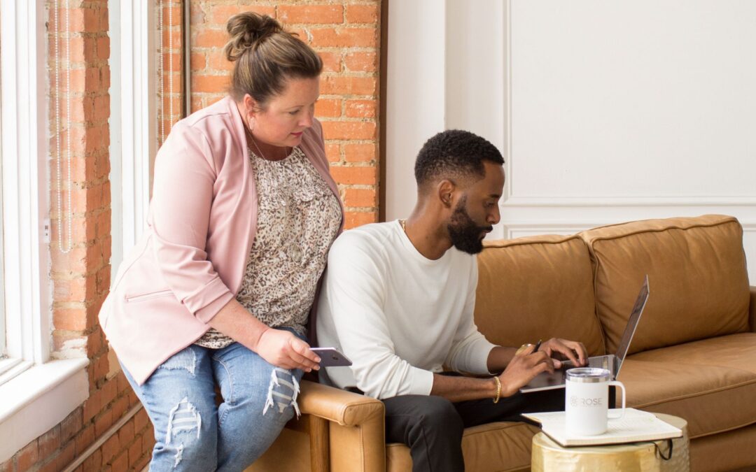 A man and woman sit on a sofa, using a laptop to work on a budget for digital child care advertising.
