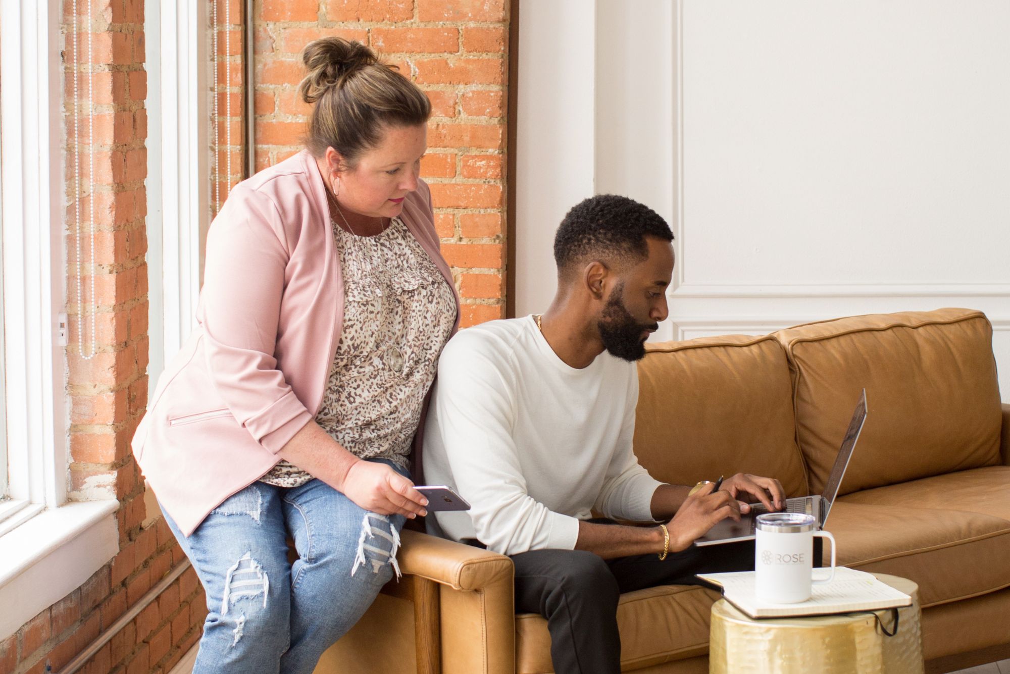 A man and woman sit on a sofa, using a laptop to work on a budget for digital child care advertising.