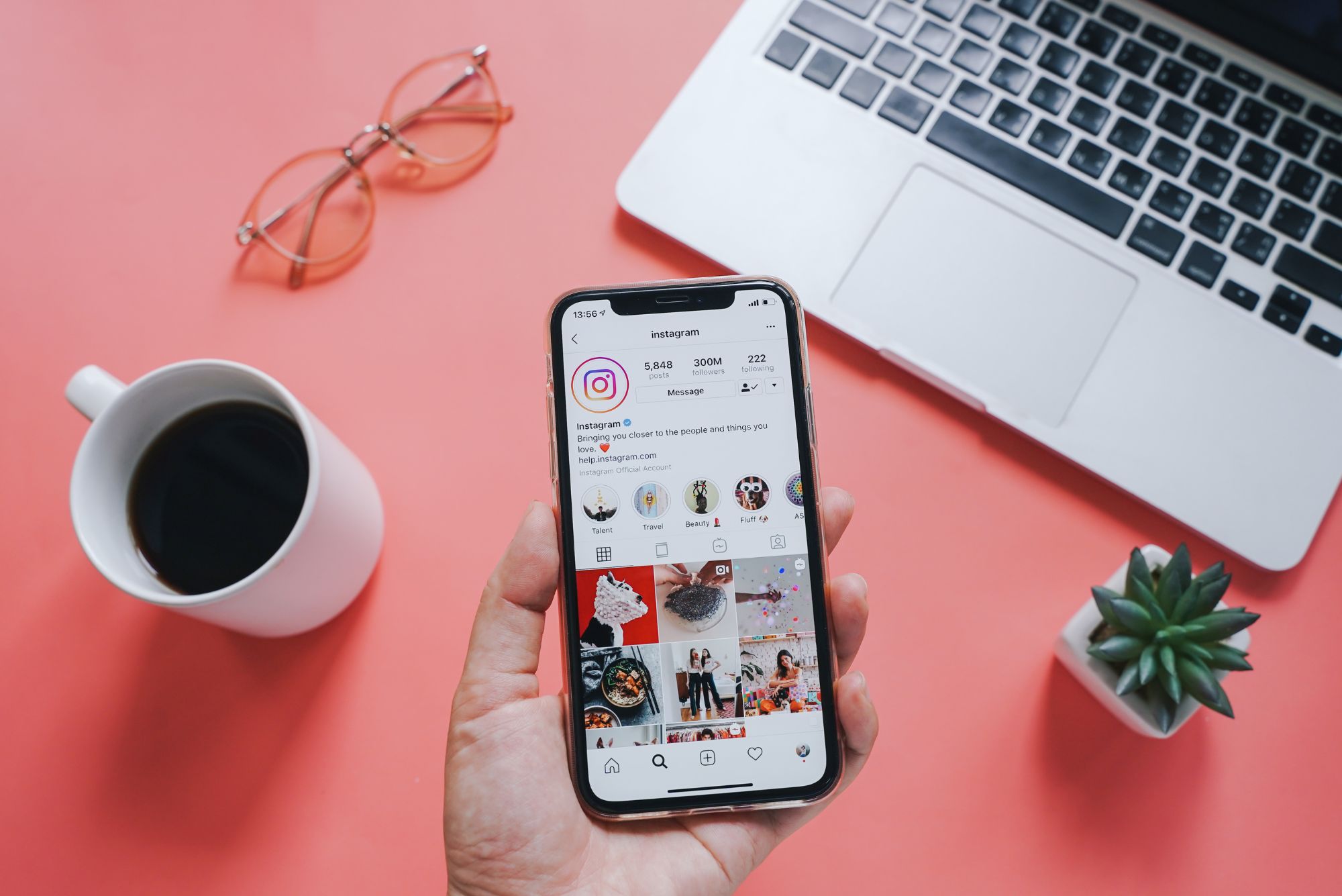 A hand shows a phone with Instagram open over a pink desk, representing social media best practices for businesses.