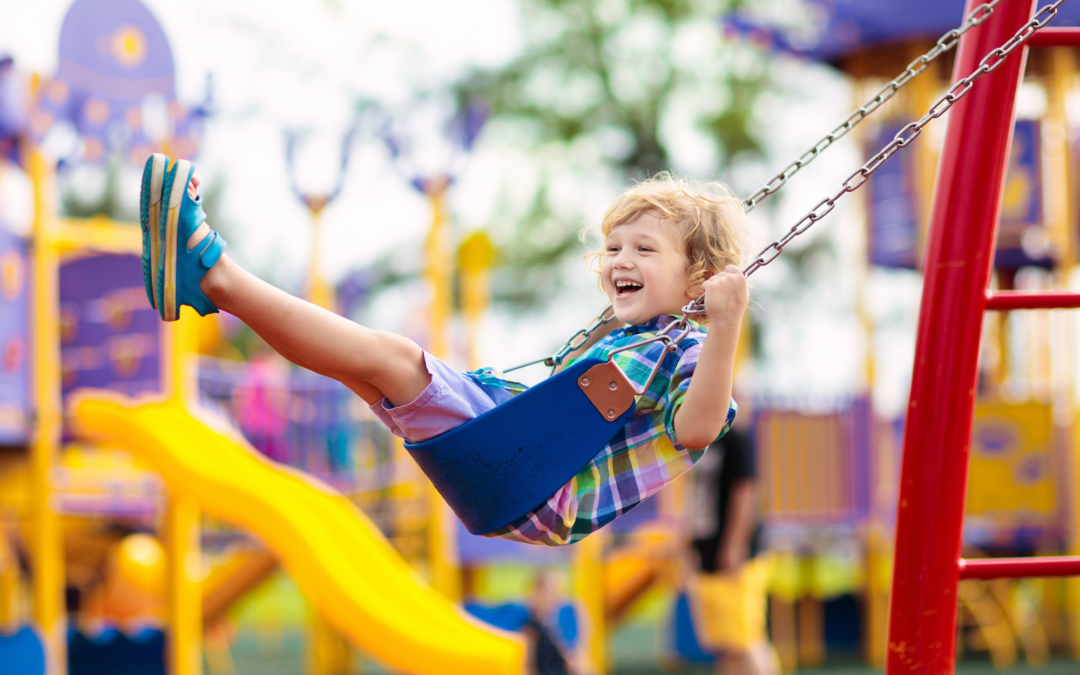 A happy child swings on his childcare center’s well-kept playground swings.