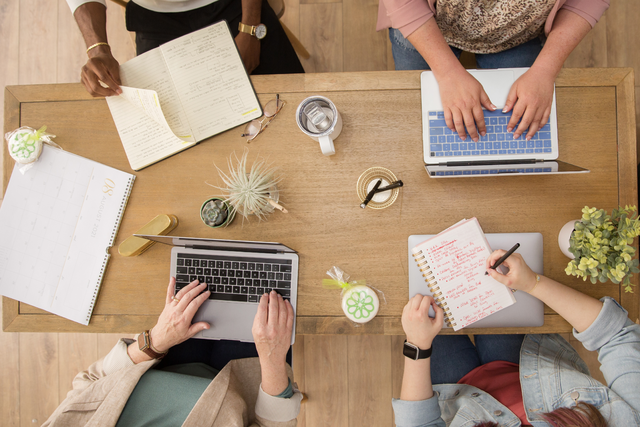 Rose Marketing Solutions' team members around a table on their laptops