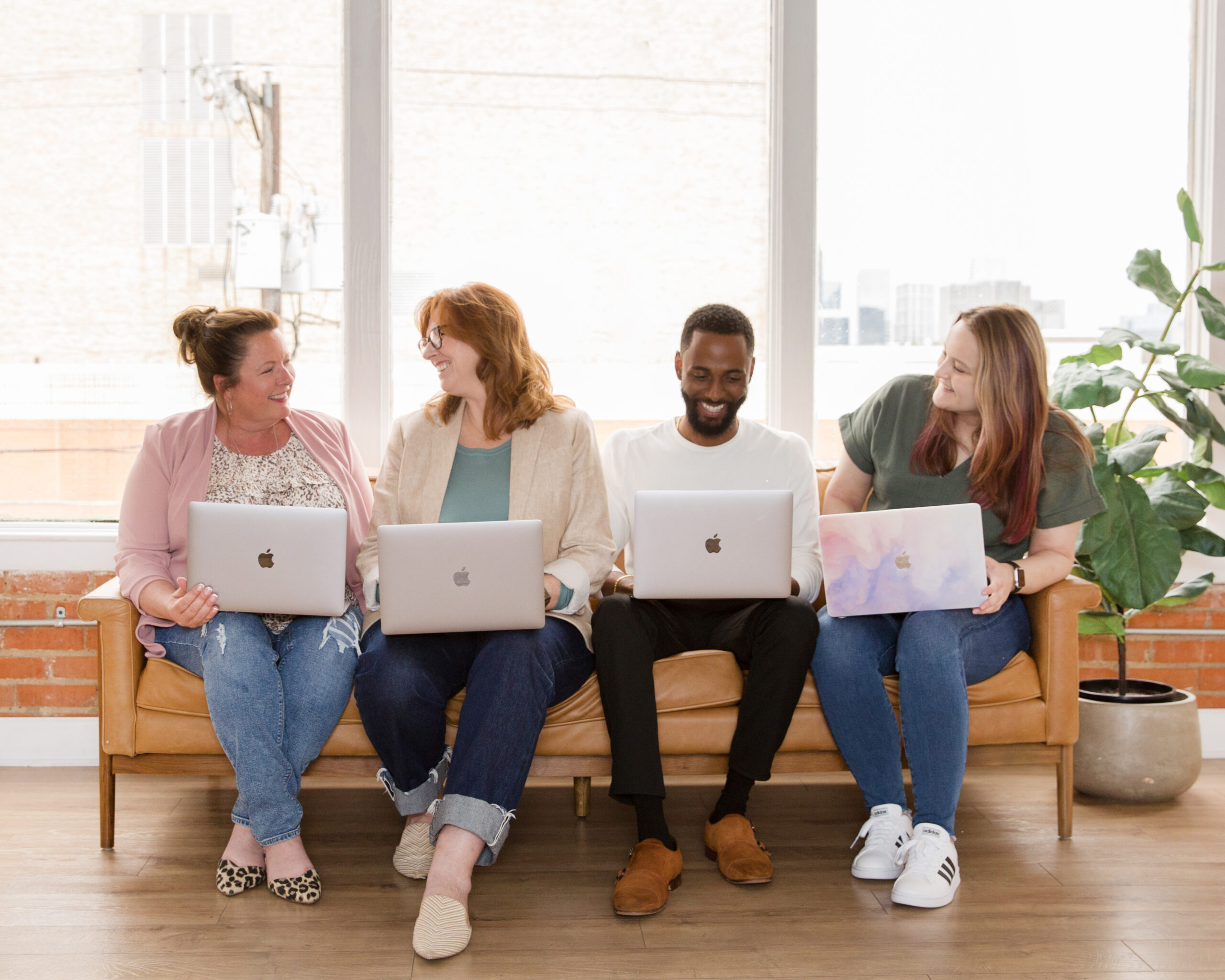 Gwen, Ruth Ann, Rashad, and Madison from Rose Marketing Solutions sitting on a couch with their laptops